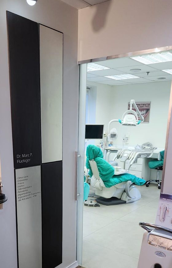 Placa com o nome do Dr. Marc e a porta de vidro abrindo para a sala de atendimento