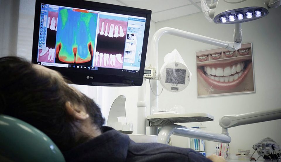 Paciente na cadeira acompanhando o exame de radiovisiografia na tela